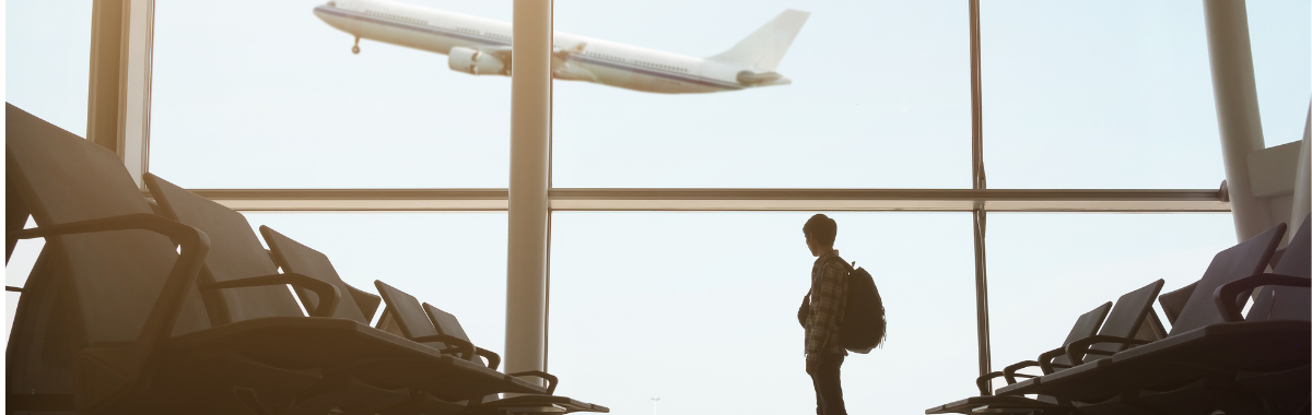 person watching plane take off from inside the airport
