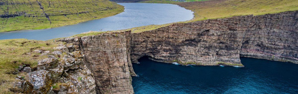 River next to a cliff edge to the ocean in the Faroe islands