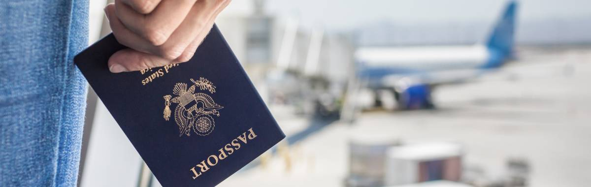 Person holding their passport while in the background they are looking at their plane