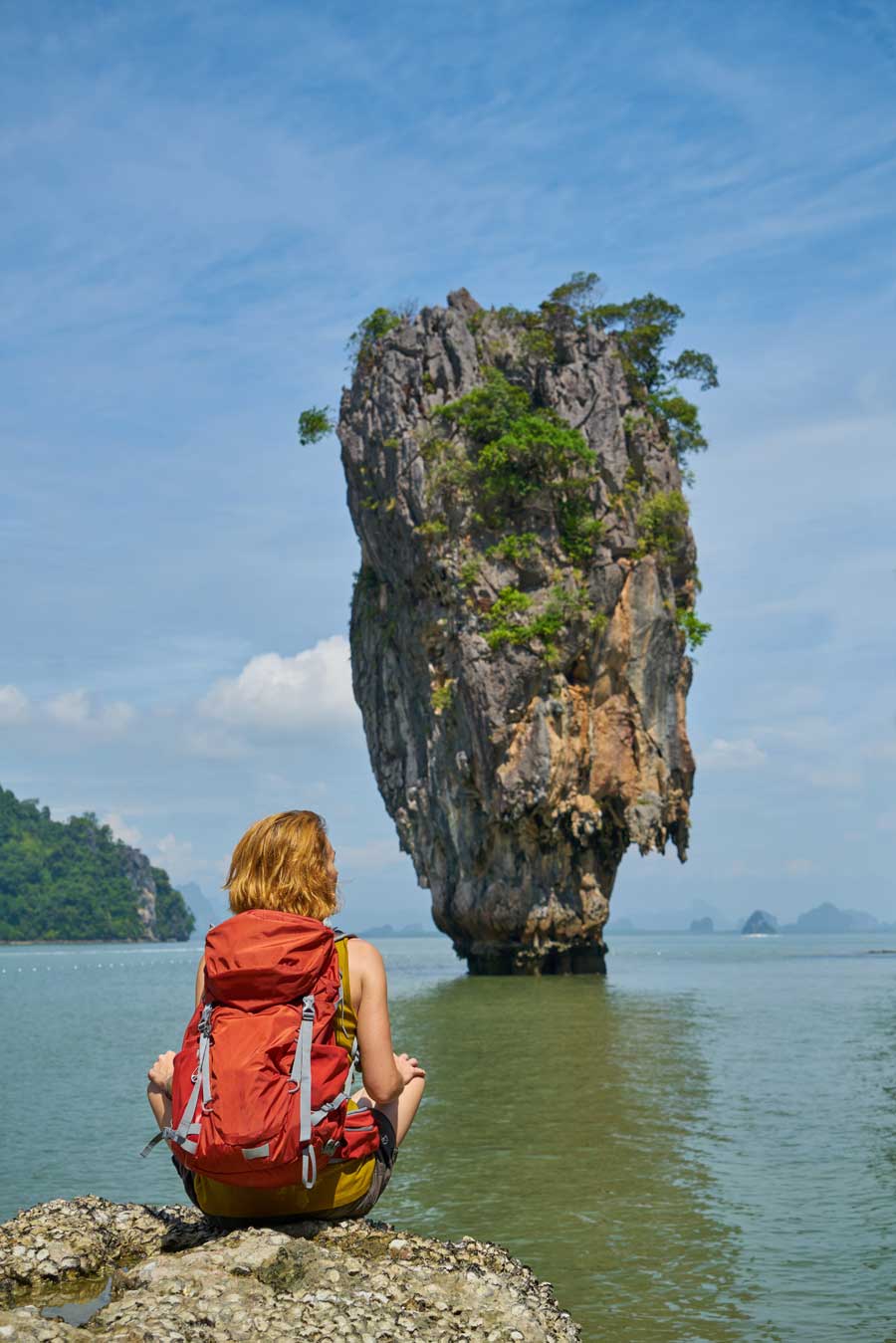 backpacker sitting in front of the ocean with an island