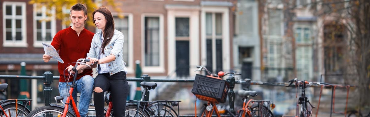 two people on a bridge in Amsterdam with bikes and a map
