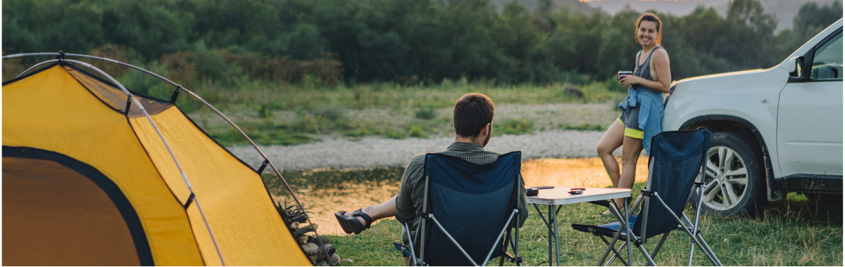 couple camping next to a tent and car