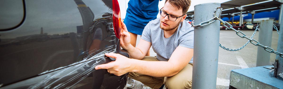 man inspecting damage to his rental car