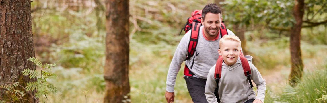 boy and dad hiking through forest