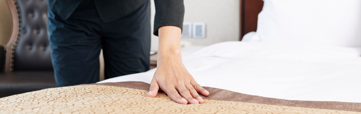 a person checks their hotel bed for bedbugs
