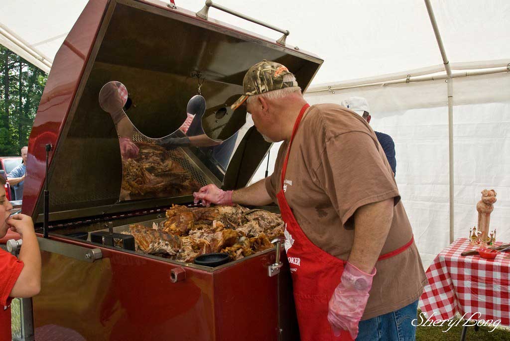 open barbecue with a person tending to the meat - north carolina porkfest