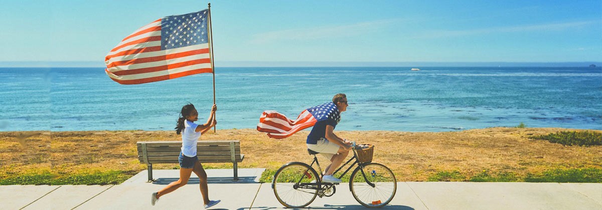 bicyclist and runner carrying american flags