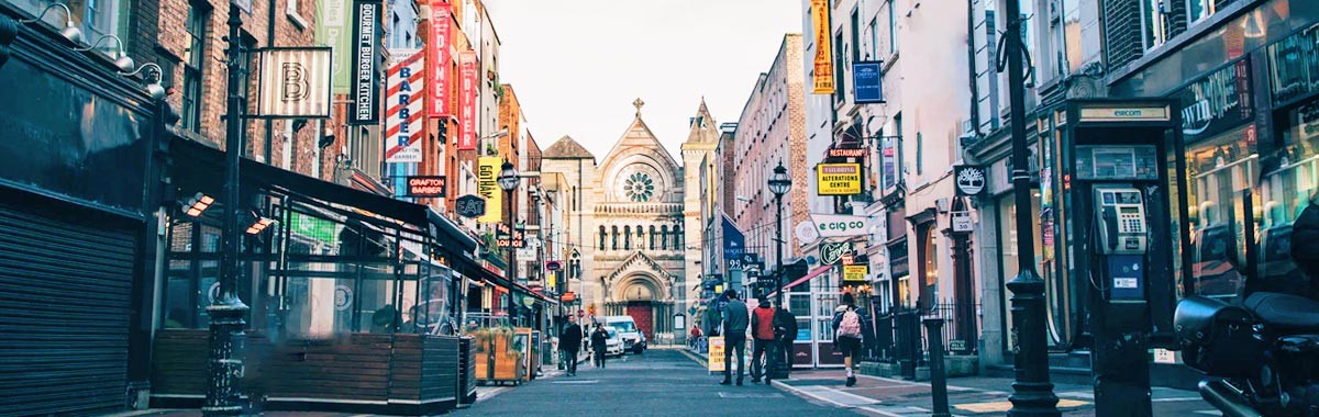 View of the streets of Dublin with storefronts and church in the distance