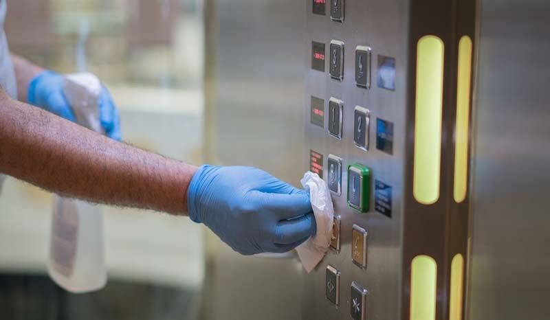 hotel worker cleans elevator buttons