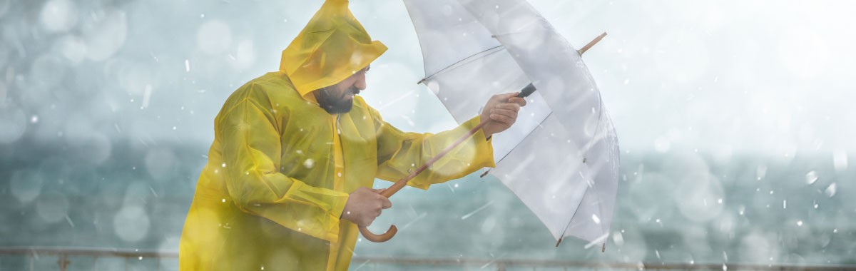 man in the rain and wind with an umbrella and yellow rain jacket