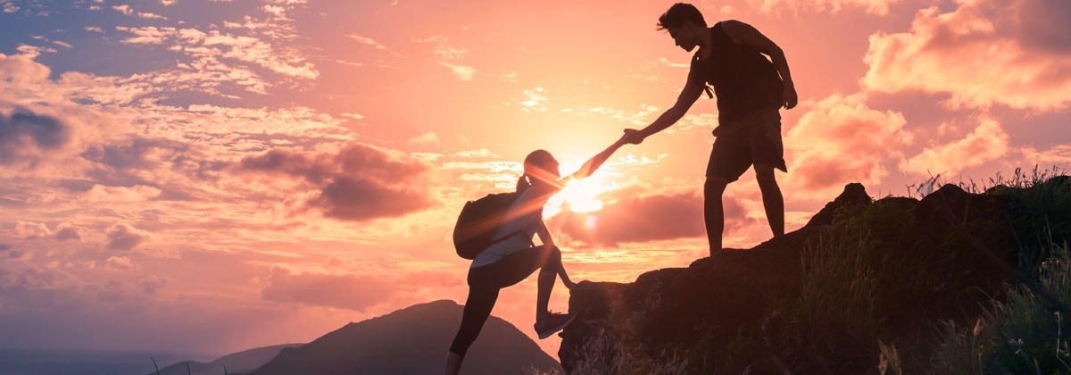 hiker giving a helping hand with sunset