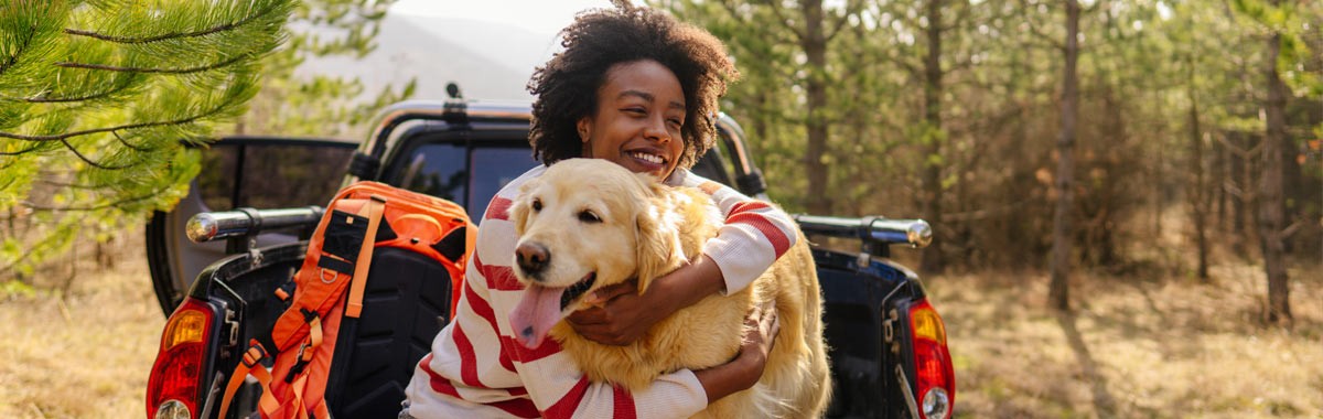 woman in back of truck with a golden retriever dog
