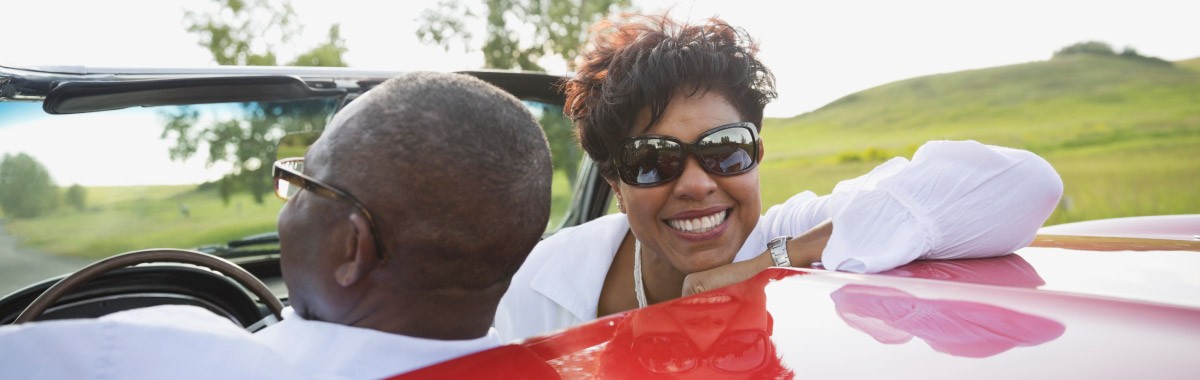 couple riding in a red convertible on vacation
