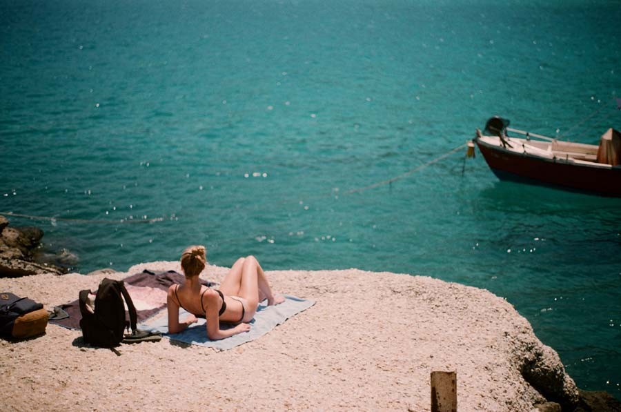 woman sunbathing on a rocky beach in crete