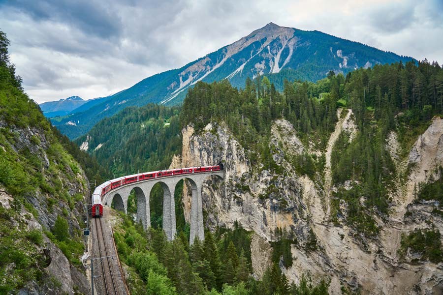 train on a bridge going through the Swiss Alps