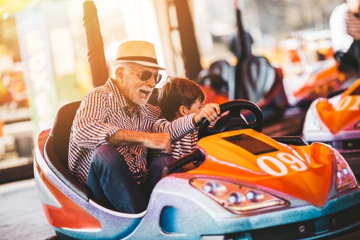 grandpa and grandson on bumper cars at theme park