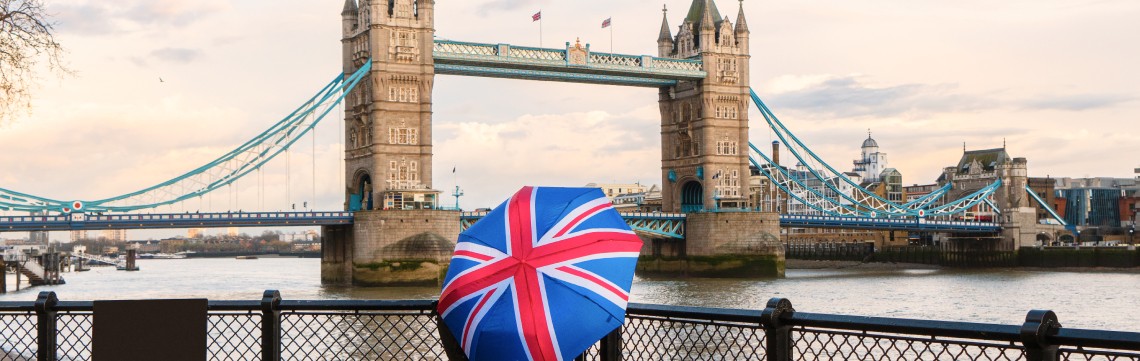 view of the London Bridge with a person holding an umbrella of the British flag