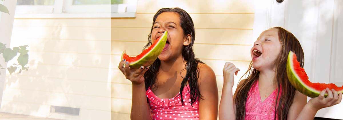 two girls eating watermelon on vacation rental porch